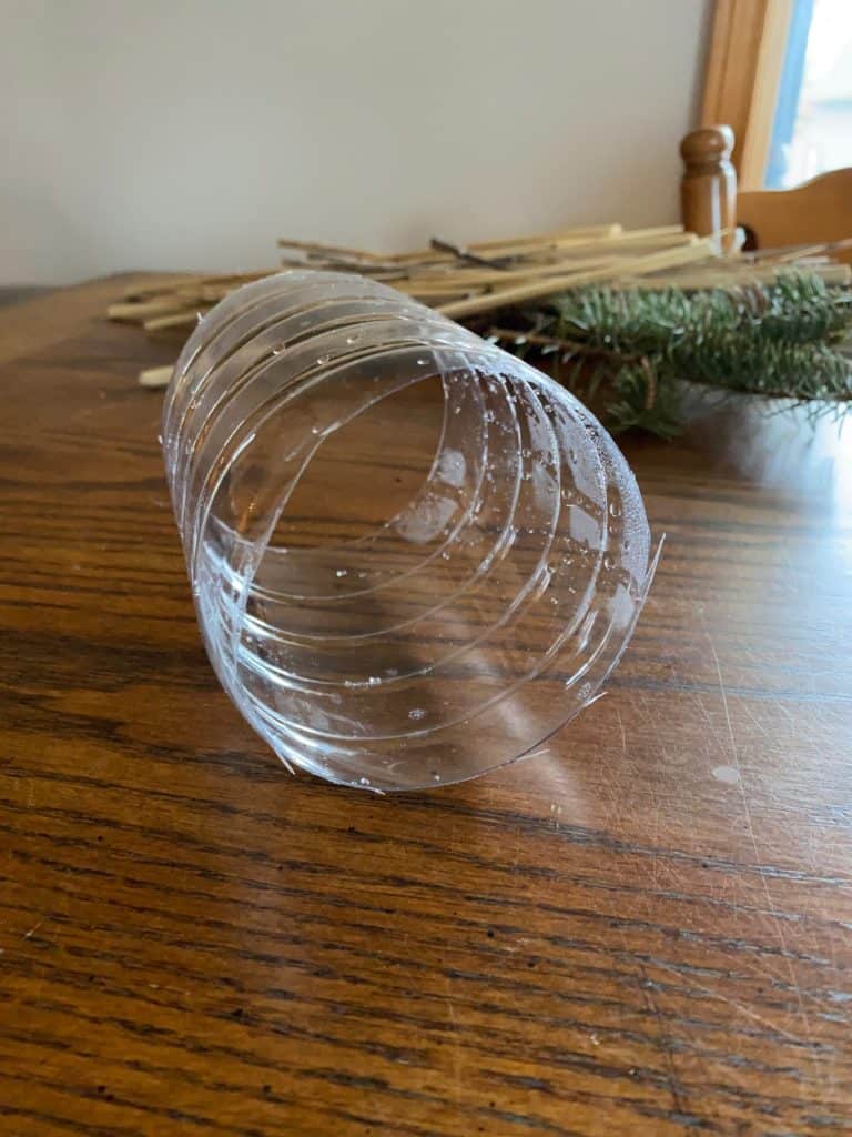 A plastic water bottle with the top and bottom ends cut off.