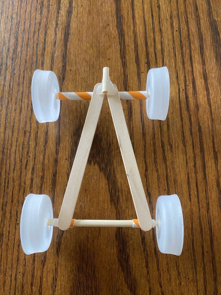 A race car made out of bottle caps, popsicle sticks, and straws.