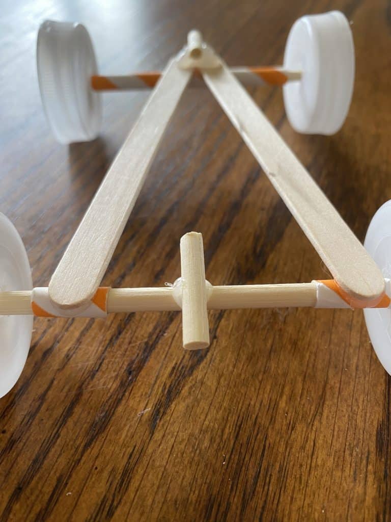 A race car made out of bottle caps, popsicle sticks, and straws.