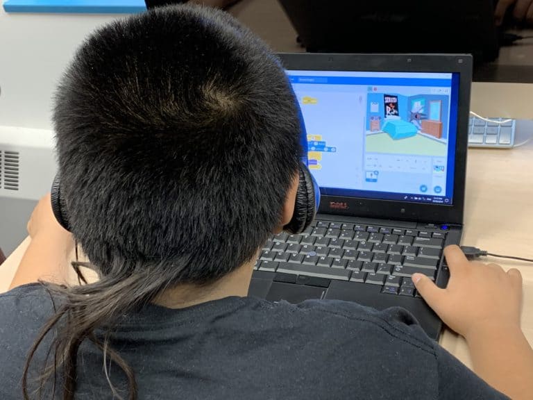 A student using a laptop to create a program in Scratch.
