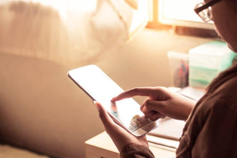 A person using a tablet. There is warm light coming in from a window.
