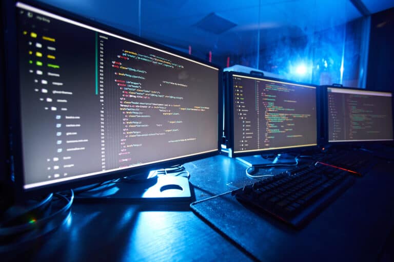 Code shown on multiple computer screens.