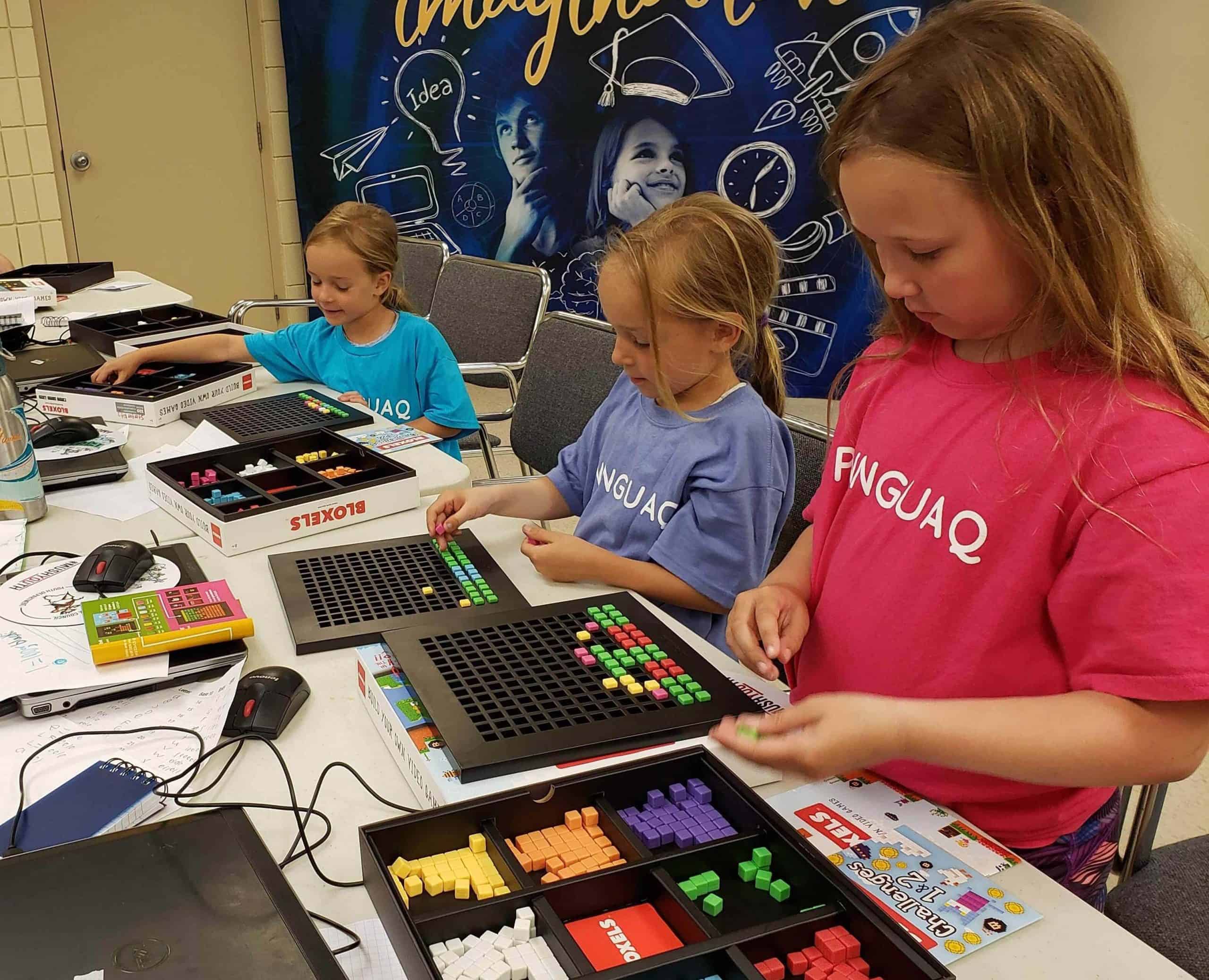 three girls in pinnguaq camp shirts building game levels using plastic blocks