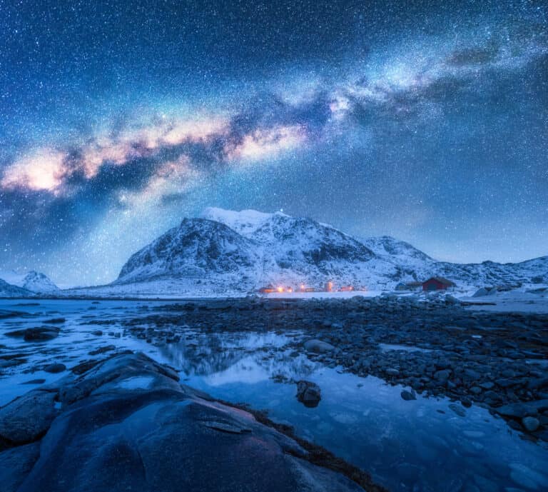 Stars shining bright over a lake and mountain.