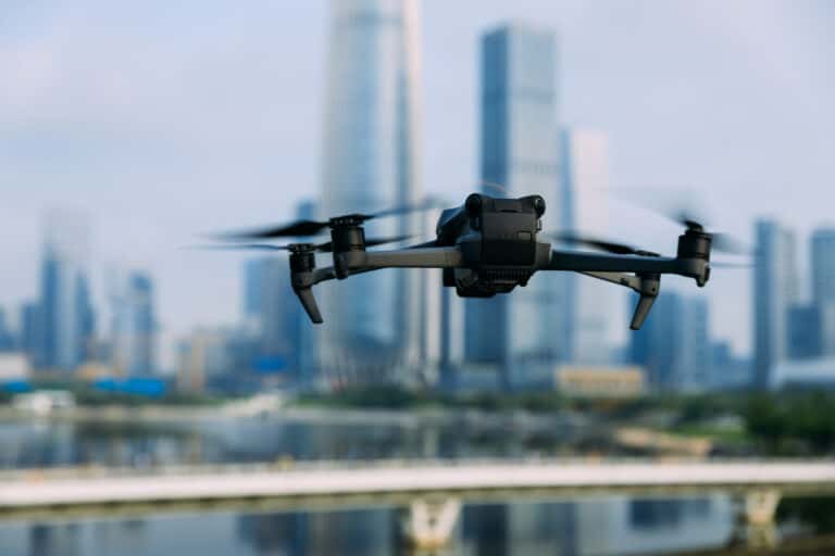 A drone flying in the air with buildings in the background.
