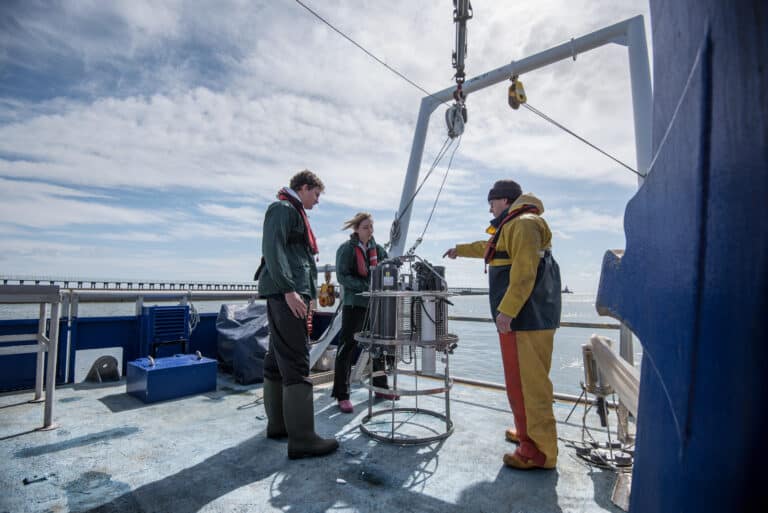 Scientist standing on a boat in the middle of the water.